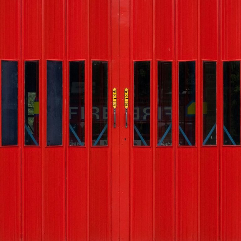 Rote, geschlossene Tore mit schwarzen Fenstern, die einen industriellen Look vermitteln.