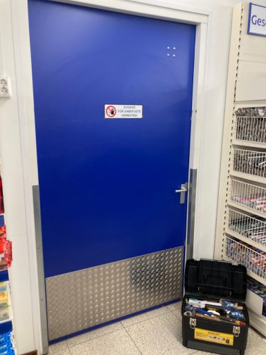 Blaue Tür mit metallischem unteren Teil und Werkzeugkasten daneben.