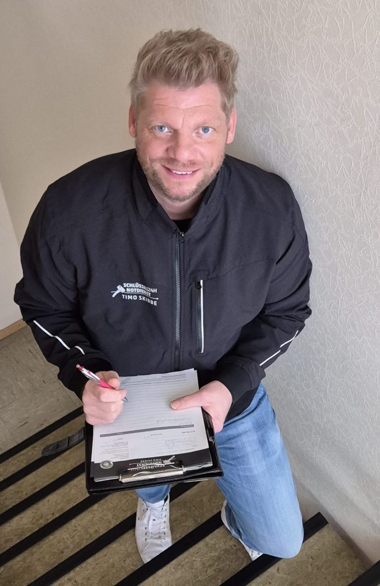 Mann mit Klemmbrett und Stift, steht auf einer Treppe.