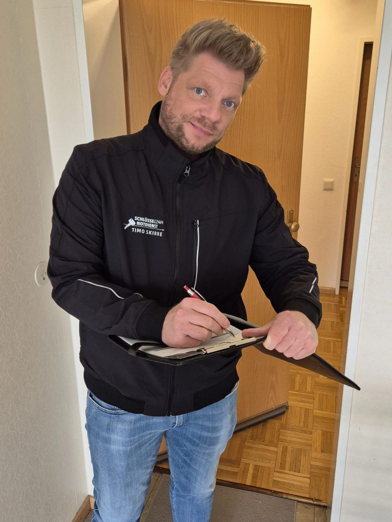 Mann in schwarzer Jacke, der mit Stift in einem Notizbuch schreibt.