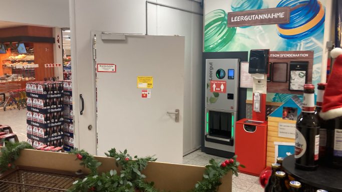 Ein Raum mit einer Tür, Getränkespender und Weihnachtsdekoration im Vordergrund.